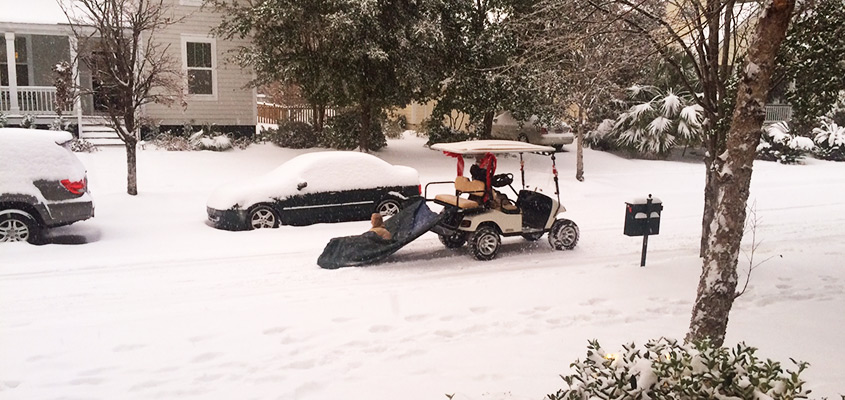 Golf cart pulls a tarp to give someone a ride in the snow in Charleston SC. © 2018 Audra L. Gibson.