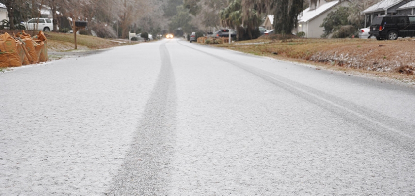 Light snow accumulates on a residential Charleston road. 